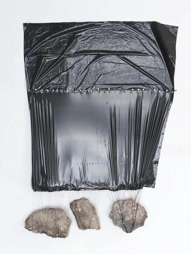 plastic bag with rocks hanging by threads