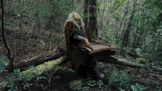 woman playing a harp in a woodland