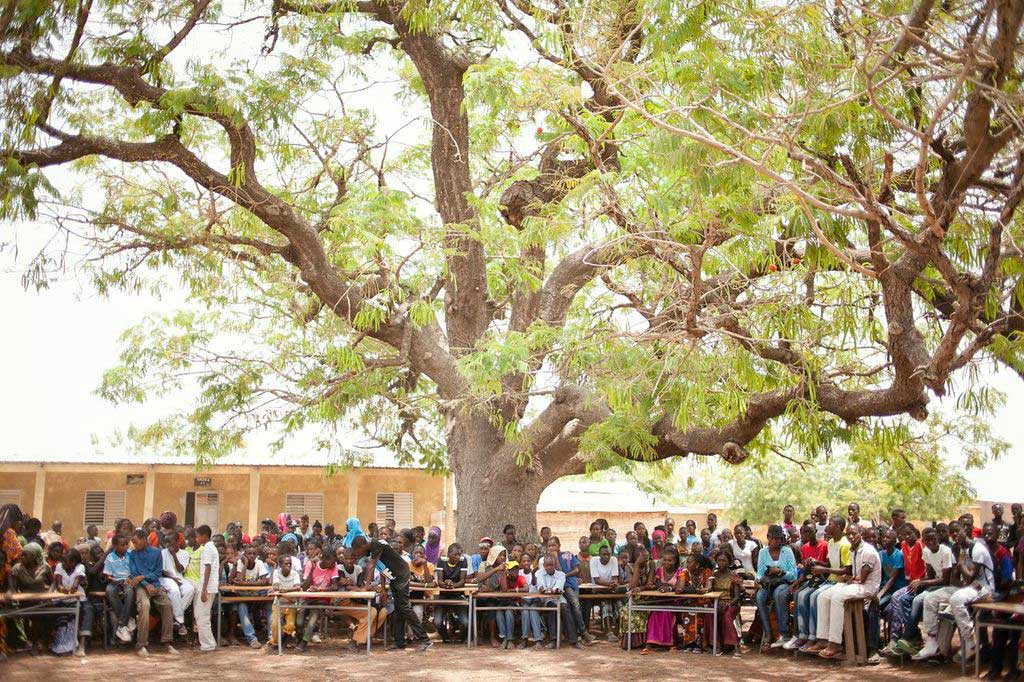 teachers and students from Senegal sitting in front of school