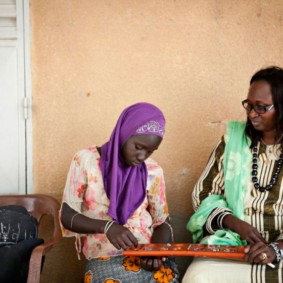 student in Senegal playing oware game while teacher looks on