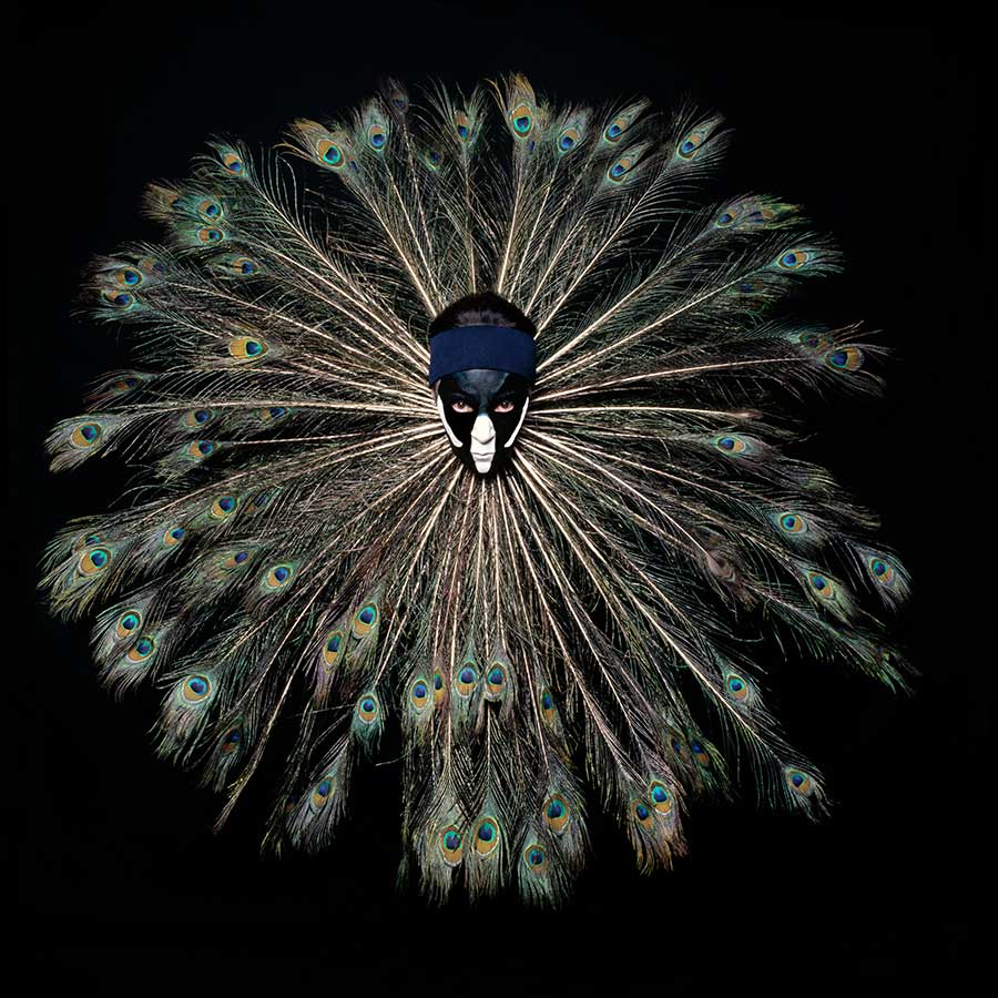 woman with peacock feathers surrounding her face