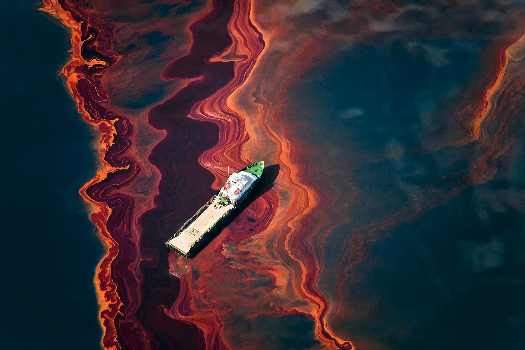 boat and oil slick in body of water