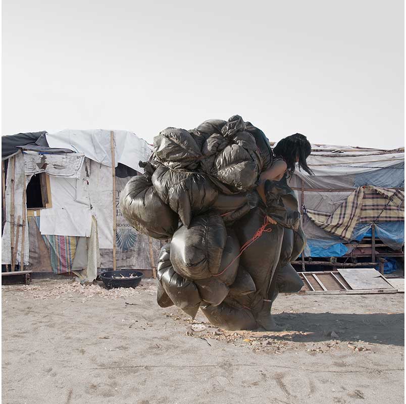 woman carrying plastic bags of belongings