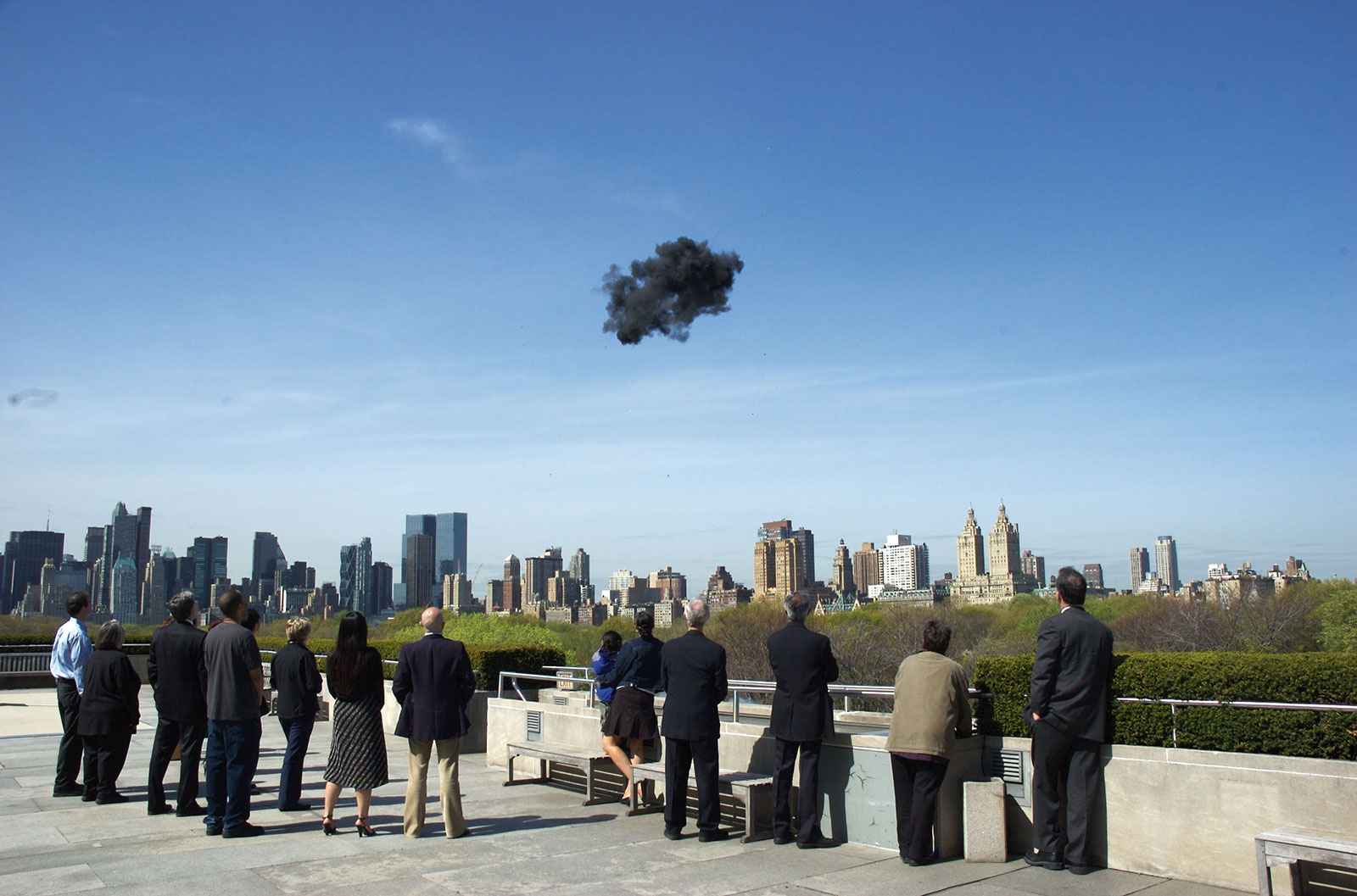 onlookers observing small black cloud in blue sky