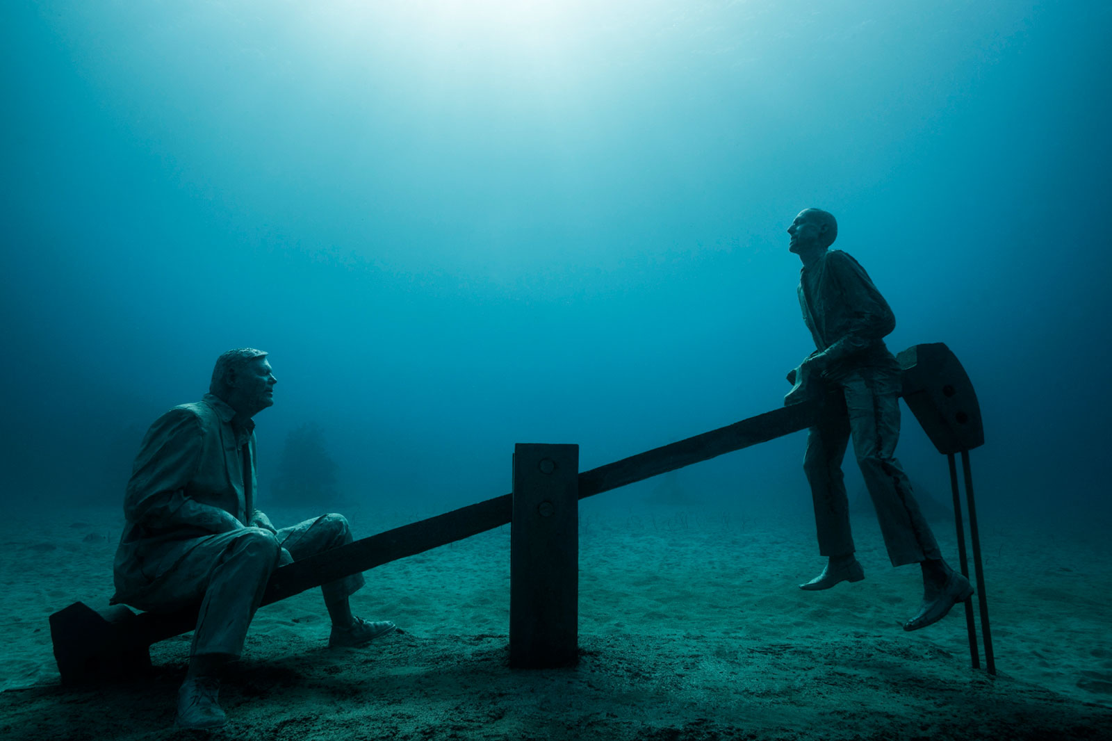 underwater sculpture of men on see saw