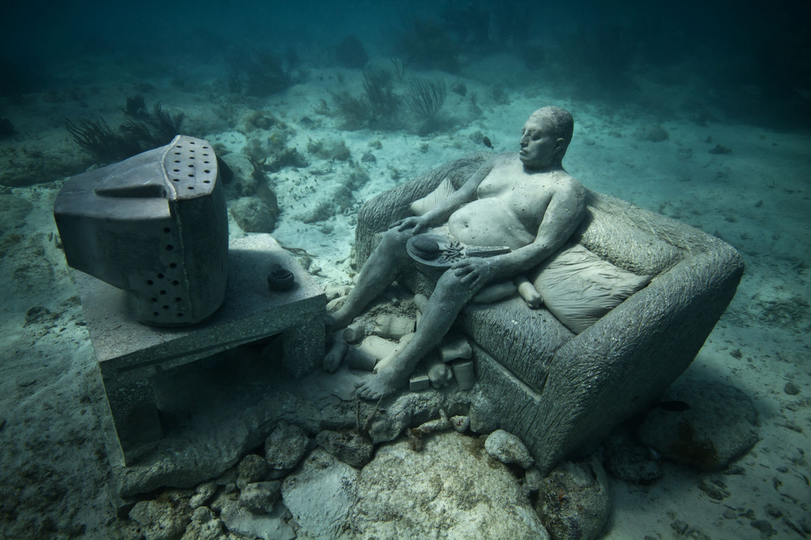 underwater sculptures of man on couch watching TV