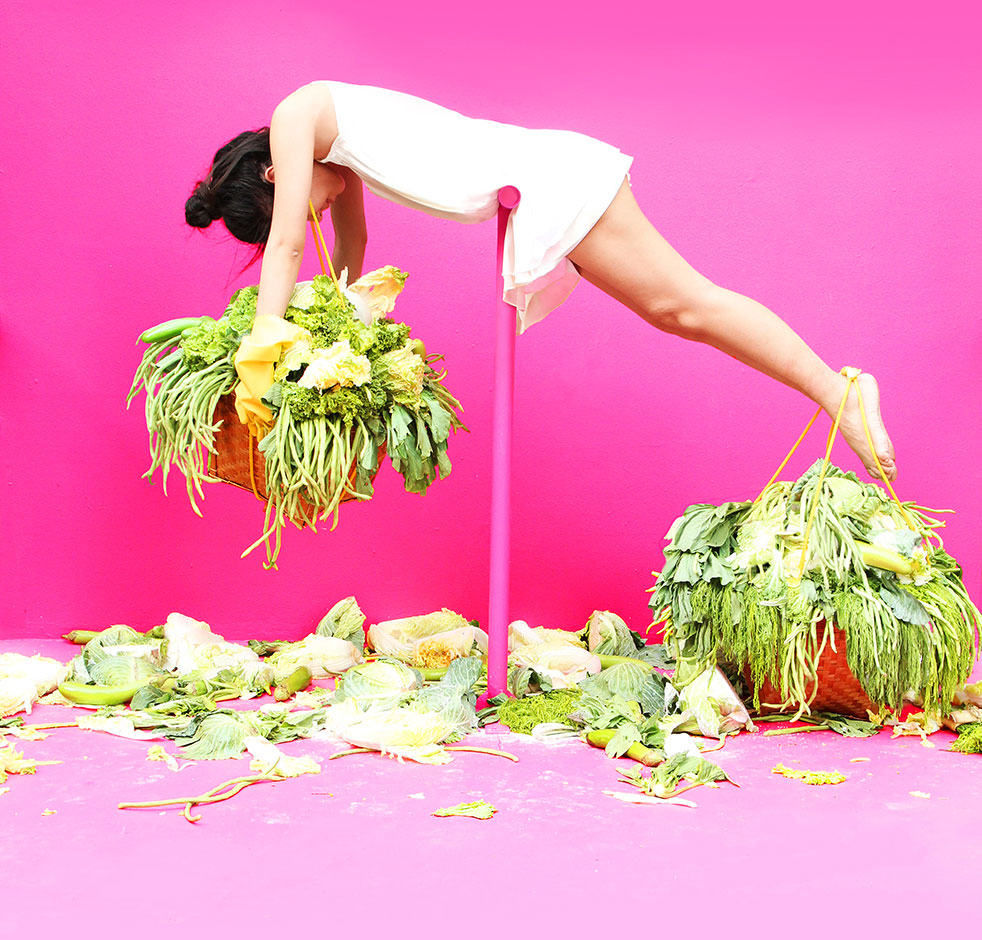 woman burdened by baskets of green produce